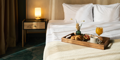 Ein Tablett mit Frühstück steht auf einem Bett in einem Hotelzimmer