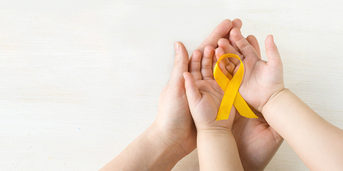Förderkreis für krebskranke Kinder Zwei Hände umschließen die Hände eines Kindes in denen ein gelbes Band liegt das für Unterstützung und Solidarität steht