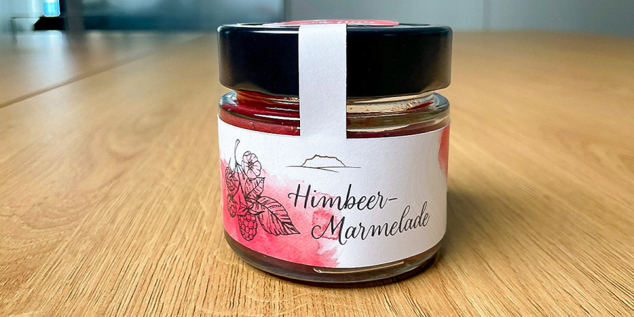 Ein Glas mit Himbeermarmelade steht auf einem Tisch
