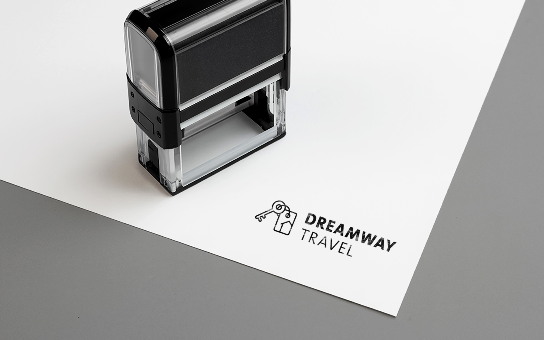 Logo von DREAMWAY TRAVEL auf einem Papierbogen, daneben steht ein Stempel