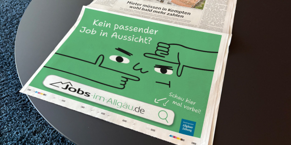 Eine Zeitung in der eine Anzeige von Jobs-im-Allgäu zu sehen ist liegt auf einem Tisch