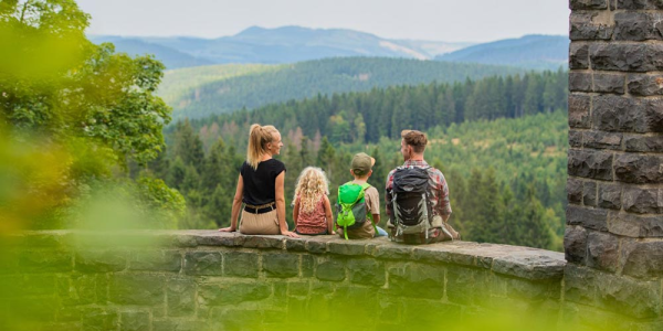 Eine Familie genießt die Aussicht auf die Berge, während sie auf einer Steinmauer sitzt