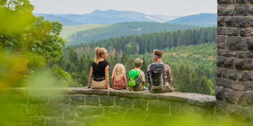Eine Familie genießt die Aussicht auf die Berge, während sie auf einer Steinmauer sitzt